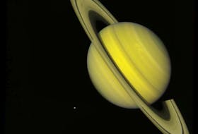 NASA Voyager 2 took this true colour photograph of Saturn on July 21, 1981, which showcases the rings around the planet. The moons Rhea and Dione appear as blue dots to the south and southeast of Saturn, respectively. - NASA image