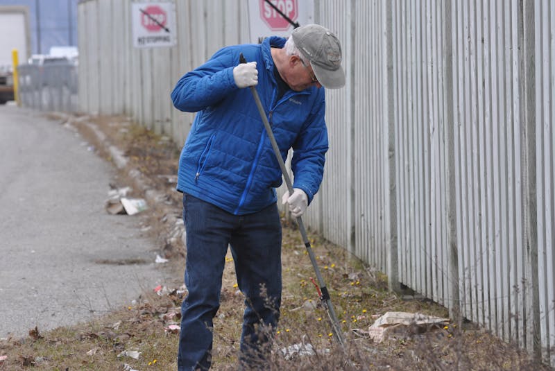 Don Taylor rakes up some of the litter that had collected near a fence on a green space on St. Mark’s Avenue in Corner Brook Thursday. — Diane Crocker