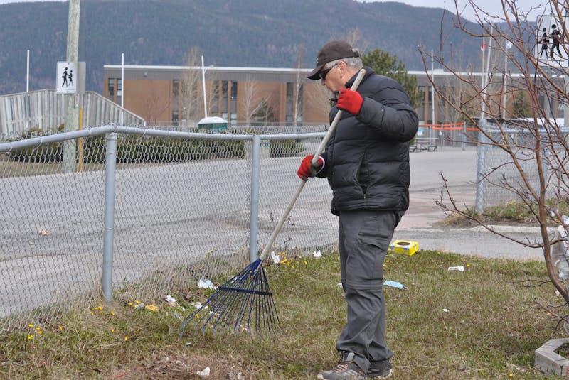 Keith Cormier rakes litter away from a fence around a green space on St. Mark’s Avenue in Corner Brook on Thursday. — Diane Crocker