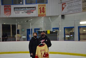 Darren and Glenda Hutchinson hold the jersey their son, Alex, wore with the Arsenault’s Fish Mart Western Red Wings at the Evangeline Recreation Centre on Wednesday night. The Red Wings defeated the Sherwood-Parkdale A&S Scrap Metal Metros 6-1 to win the best-of-seven Island Junior Hockey League championship series 4-1. Alex died in September when a boat he was in capsized near Alberton. The Red Wings retired Alex’s No. 14 in November, and dedicated the 2020-21 season to him.
