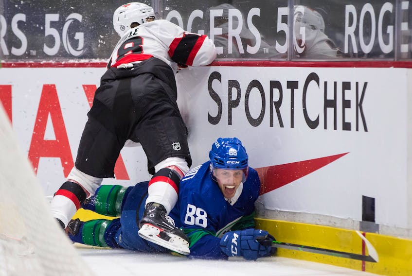 Ottawa Senators' Tim Stuetzle misses the check on Vancouver Canucks' Nate Schmidt and crashes into the boards on Thursday night.