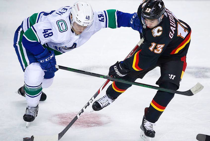 Olli Juolevi, seen battling Johnny Gaudreau of the Flames in a February contest, will stay with the Canucks as the team shuffles its roster.
