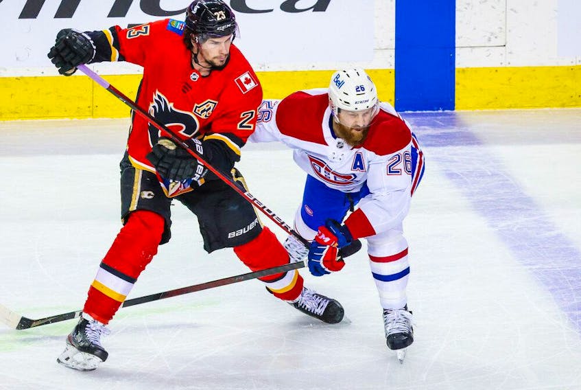 Flames' Sean Monahan (23) and Canadiens defenceman Jeff Petry  battle for the puck during the first period at Scotiabank Saddledome in Calgary on Saturday, April 24, 2021. 