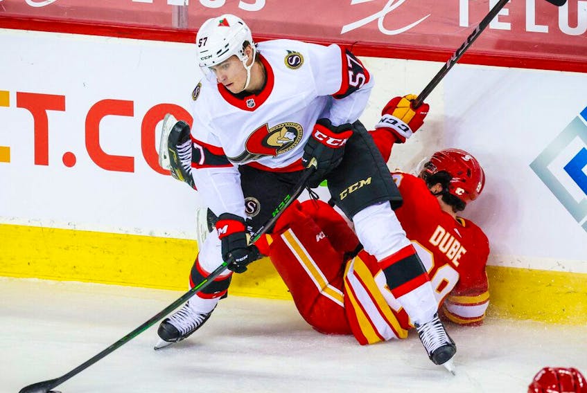  Senators centre Shane Pinto plays the puck away from fallen Flames re Dillon Dube during the third period of an April 19 game in Calgary.
