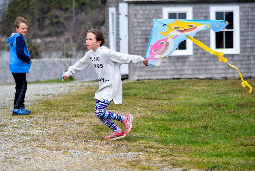 A young girl runs with her kite trying to get it airborne at the Historic Acadian Village in Pubnico on April 21. KATHY JOHNSON