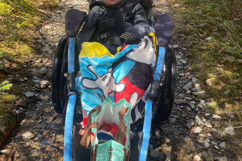 Five-year-old Lyndon is all smiles earlier this month when he was able to travel the LaManche Park trail with his mother, Adina Stamp, and his brother, Zander, thanks to a specialized wheelchair, which his family borrowed from the Janeway children's hospital. - Contributed