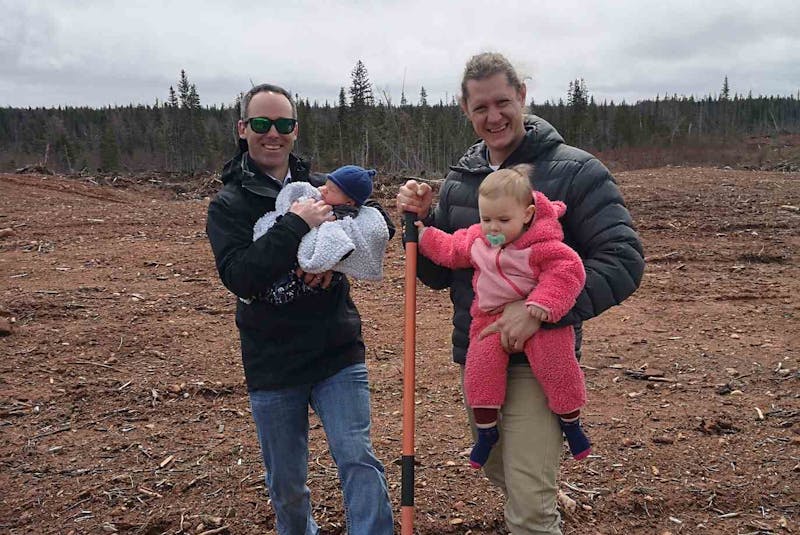 Adam Anderson, left, holding his son William, and Lukas Doman, holding his daughter Stella, are getting into the potato farming business. They’ll be developing this property at Dead Water Brook in Cormack. - Contributed