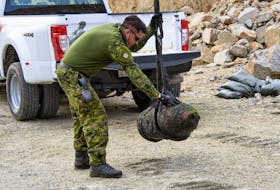 Petty Officer Second Class Tom Amos, guides the UXO to its final position at the disposal site PHOTO: MASTER CORPORAL IAN THOMPSON, CANADIAN ARMED FORCES

