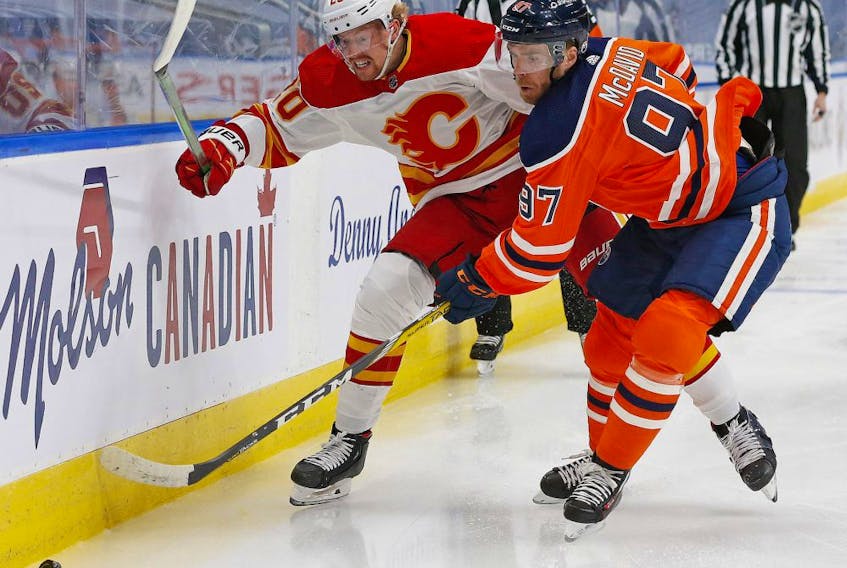 Calgary Flames forward Joakim Nordstrom (20) and Edmonton Oilers forward Connor McDavid (97) chase a loose puck during the first period  at Rogers Place on April 2, 2021. 