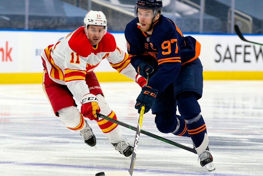 The Edmonton Oilers' Connor McDavid (97) battles the Calgary Flames' Mikael Backlund (11) at Rogers Place, in Edmonton on Thursday, April 29, 2021.