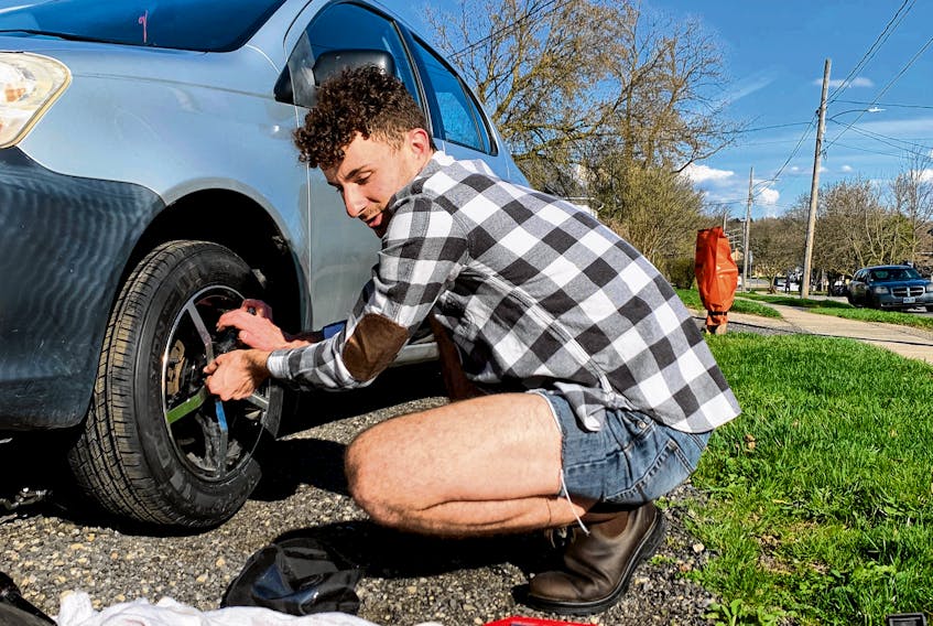 Jacob Maxwell changing from winter tires to summer ones in the driveway of the student house where he rents a room. 
