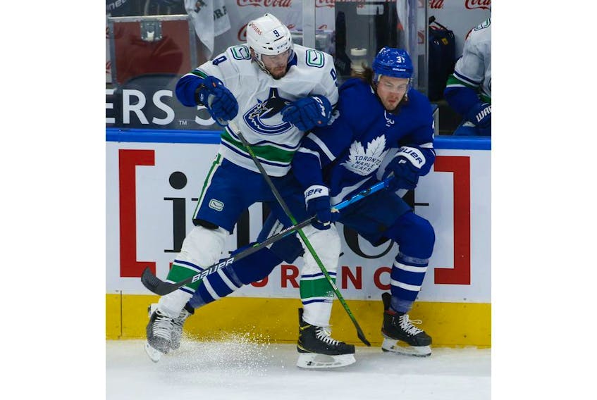 Vancouver Canucks J.T. Miller C (9) takes out Toronto Maple Leafs Justin Holl (3) along the boards during the first period in Toronto on Thursday April 29, 2021. Jack Boland/Toronto Sun/Postmedia Network