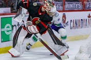Ottawa Senators goaltender Marcus Hogberg loses a puck battle behind his net with Vancouver Canucks centre Tyler Motte, April 28, 2021.