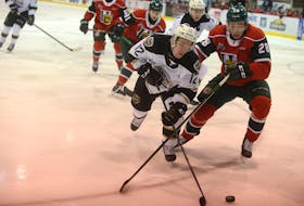 Charlottetown Islanders winger Keiran Gallant, left, looks to play the puck behind the Halifax Mooesheads net while Stephen Davis defends Sunday during Quebec Major Junior Hockey League action in Charlottetown.