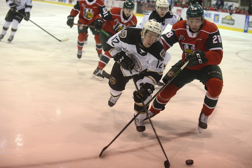 Charlottetown Islanders winger Keiran Gallant, left, looks to play the puck behind the Halifax Mooesheads net while Stephen Davis defends Sunday during Quebec Major Junior Hockey League action in Charlottetown. - Jason Malloy