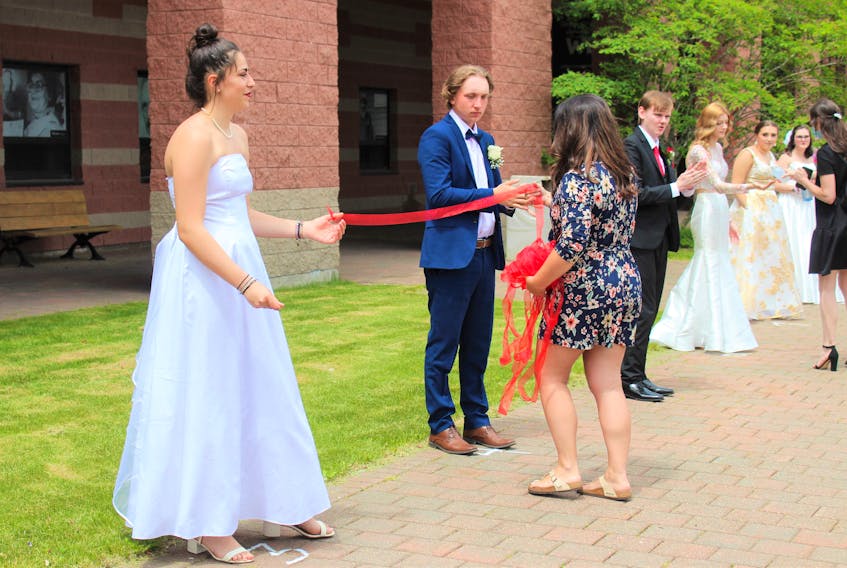 Glace Bay High School's grand march was held at CBU last year since the COVID-19 pandemic forced the cancellation of tradition prom events. From left, then 17-year-old Vittoria Amoria from Terni, Italy, and then 18-year-old Bryson Aucoin, are given the ribbon they must hold to ensure they stay six feet apart from Sandra Johnson, a volunteer parent. CAPE BRETON POST FILE PHOTO 