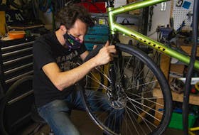 Roger Nelson, co-owner of Halifax Cycles & Guitars, works on a bike in his Halifax shop on Tuesday.