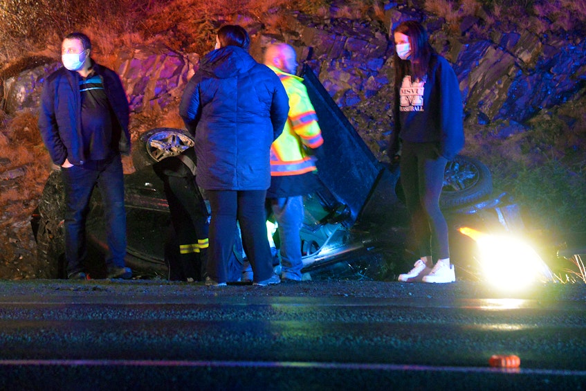 Passersby who were helping at a crash scene on Peacekeepers Way Friday night wait for firefighters to arrive on scene. Keith Gosse/The Telegram