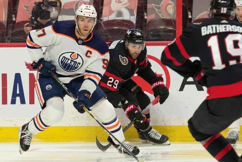 Edmonton Oilers centre Connor McDavid (97) carries the puck ahead of Ottawa Senators centre Michael Amadio (29) at the Canadian Tire Centre on Thursday, April 8, 2021.