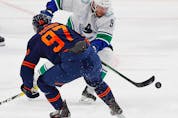 Vancouver Canucks forward J.T. Miller chips the puck past Oilers forward Connor McDavid in the second period.