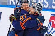 Oilers forward Connor McDavid celebrates his 100th point of the season on a goal by forward Leon Draisaitl against the Vancouver Canucks at Rogers Place in Edmonton Saturday.