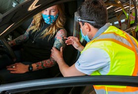 Kelly Clark receives her COVID-19 vaccine by nurse, Kevin Orrel at the province's first drive-thru vax site in Dartmouth Monday May 10, 2021.  CNS/POOL PHOTO