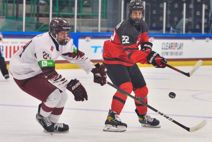 Canada's Dylan Guenther (No. 22) makes a pass in front of Martins Sulcs (No. 24) of Latvia in a group game at the IIHF U-18 world championships in Frisco, Texas, on April 28, 2021.