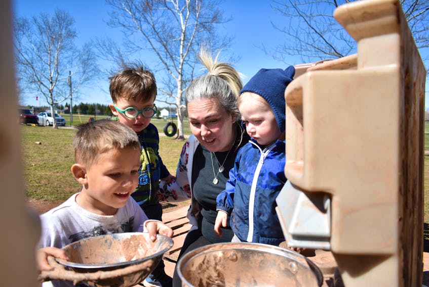 Albany Cluney, 4, left, Ronin Mooney, 2, Nolan Shaw, 2, and owner/director Jamie Mosher spend a sunny afternoon making mud cakes in the outdoor kitchen at Rainbow Beginnings Early Learning Centre Inc. in St. Theresa on May 11. 