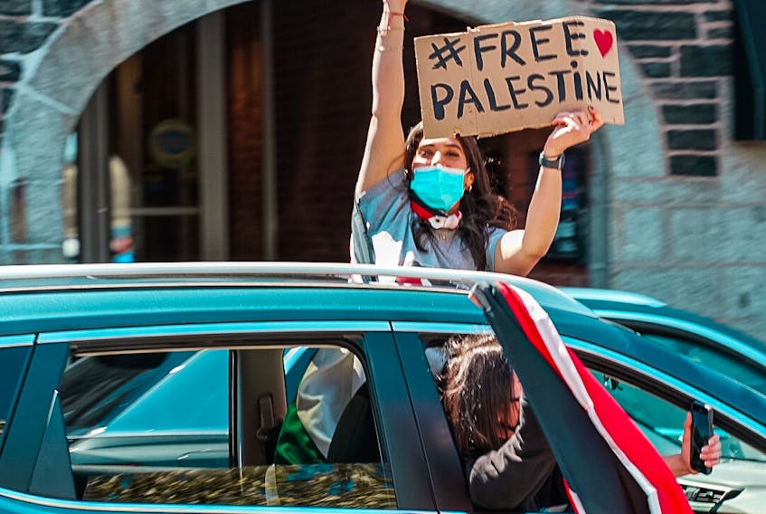 A protester peaks out of a car's sunroof during the #FreePalestine rally in Halifax Saturday, May 15, 2021. Photo Credit: Mohammed Al-Karmanji