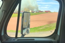 A motorist travelling on Route 2 in Springvale took this picture of firefighters in the distance battling a blaze that destroyed two buildings on Monday afternoon.