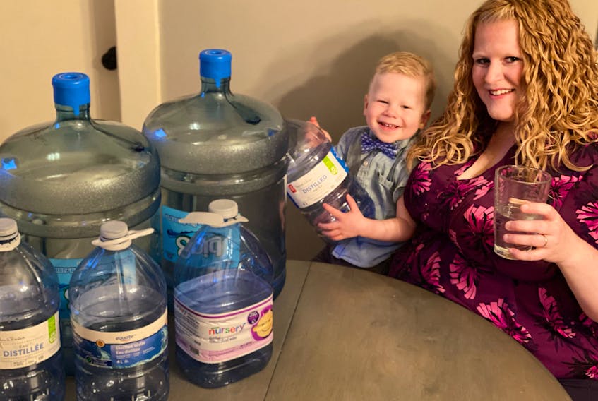 Courtney Boudreau and her son Tucker with some of the jugs the family uses to lug water when the well at their Yarmouth County home goes dry. TINA COMEAU • TRICOUNTY VANGUARD
