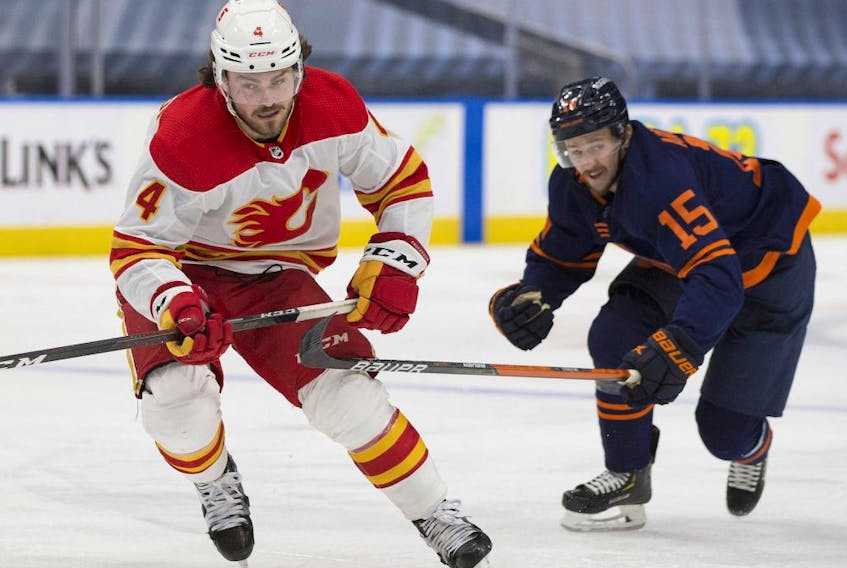 Edmonton Oilers Josh Archibald (15) and Calgary Flames Rasmus Andersson (4) skate for the puck during second period NHL action on Saturday, May 1, 2021 in Edmonton. 