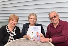 Regis Duffy, right, holds a copy of The Chemistry of Innovation: Regis Duffy and the story of DCL (Diagnostic Chemicals Limited) with his wife Joan Duffy, left, and daughter Mo Duffy Cobb. The book was co-written by Cobb and Lori Mayne.