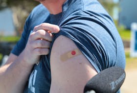 Nova Scotia Premier Iain Rankin proudly shows off his bandage — with a smiley face — on his arm after getting his first shot of the COVID-19 vaccine at a clinic at the Halifax Forum Multi-Purpose Centre Monday.