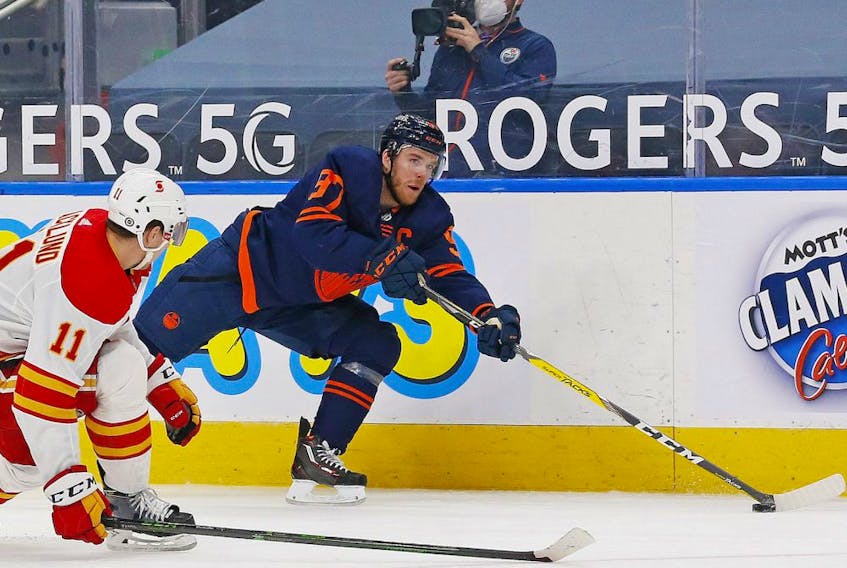 Edmonton Oilers forward Connor McDavid (97) tries to make a pass in front on Calgary Flames forward Michael Backlund (11) during the third period at Rogers Place on May 1, 2021. 