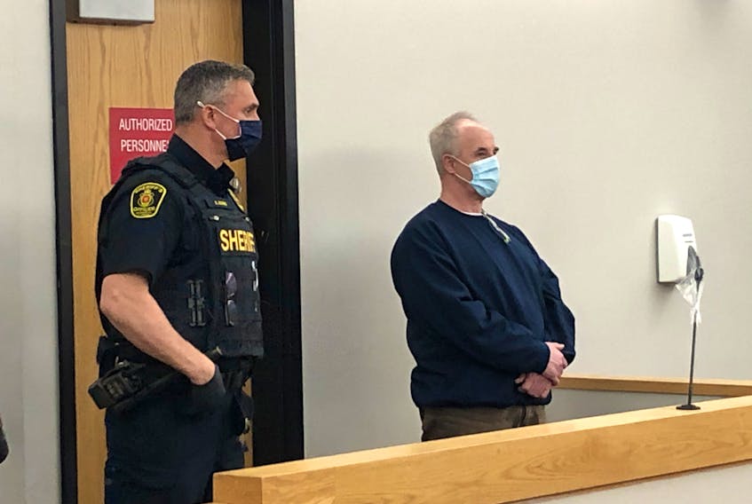 Escorted by sheriffs, Dennis Murphy (right) stands as provincial court Associate Chief Judge Mike Madden enters the courtroom for his sentencing in St. John's Monday.