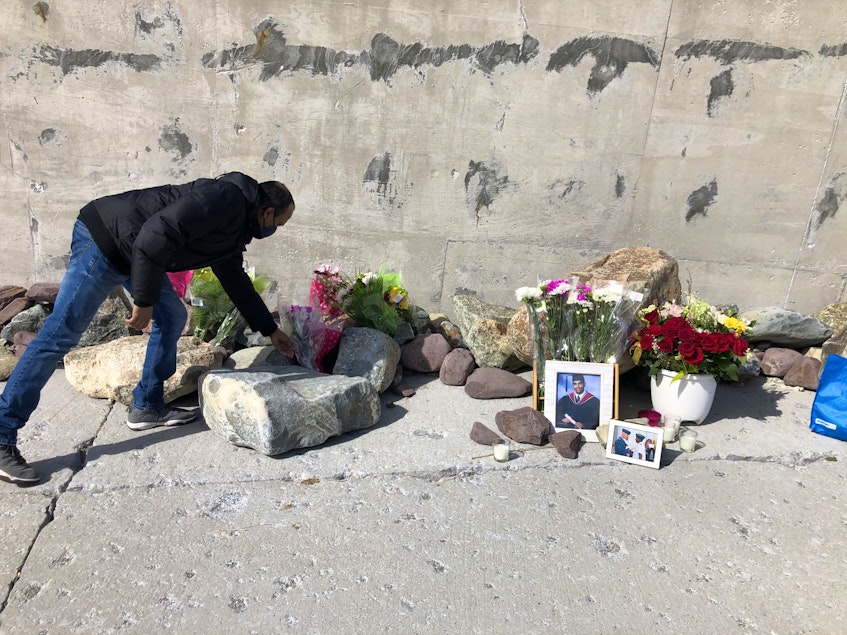 A man places flowers at the memorial. — Joe Gibbons/The Telegram