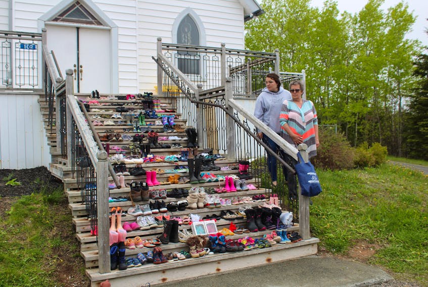 Gina Hrachy left, and Maxine Kennedy, both of Mira Road, add their contributions to the shoes left on the steps of St. Anne's Church in Membertou. IAN NATHANSON/CAPE BRETON POST