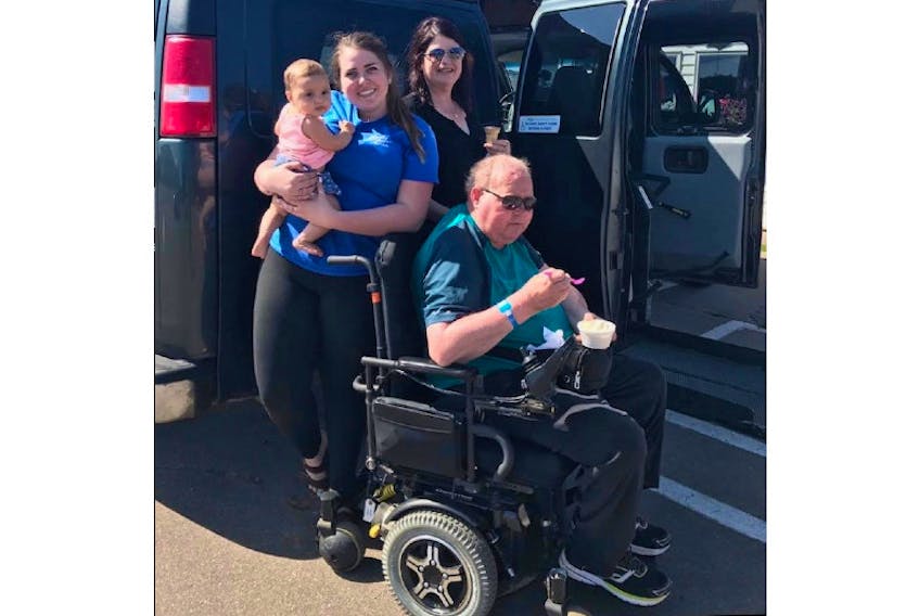 Taylor Pound, left, holding a baby cousin, stands with her mom, Betty Pound, and her father, Allan Pound, seated in his wheelchair, at Marco Polo Land in August 2017. The Pounds passed on the van when Allan died and it continues to be donated to new owners.