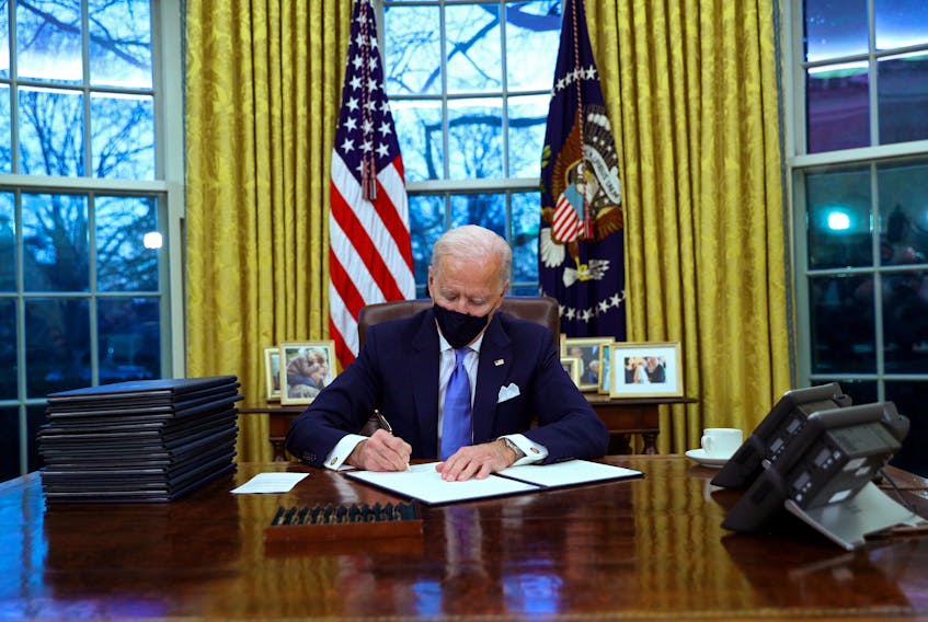 U.S. President Joe Biden signs executive orders in the Oval Office after his inauguration Jan.20, 2021. REUTERS/Tom Brenner
