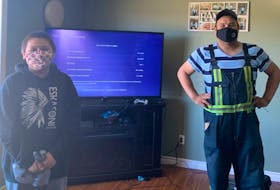 Twelve-year-old Allan Sylliboy is all smiles under his mask as Arin Stevens, a technician with Eskasoni Communications, installs high-speed Internet to the home. CONTRIBUTED