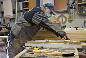 Robbie Lynds cutting wood at his tool- and material-filled workshop in Valley, Colchester County.