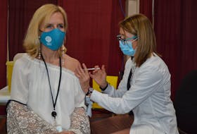 Deanne Burnet, right, a registered nurse, administers the Pfizer vaccine to Dr. Heather Morrison, left, P.E.I.’s chief public health officer, at the mass vaccination clinic in Charlottetown on Thursday.