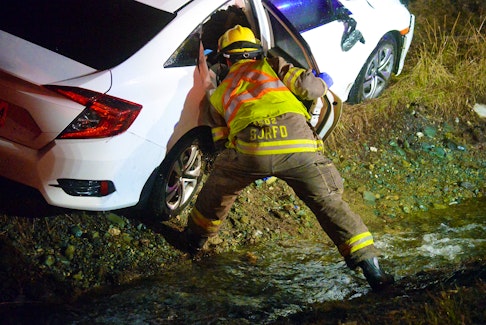Firefighters check on a female driver following a crash at the Peacekeepers Way/Pitts Memorial cloverleaf Saturday night. Keith Gosse/The Telegram