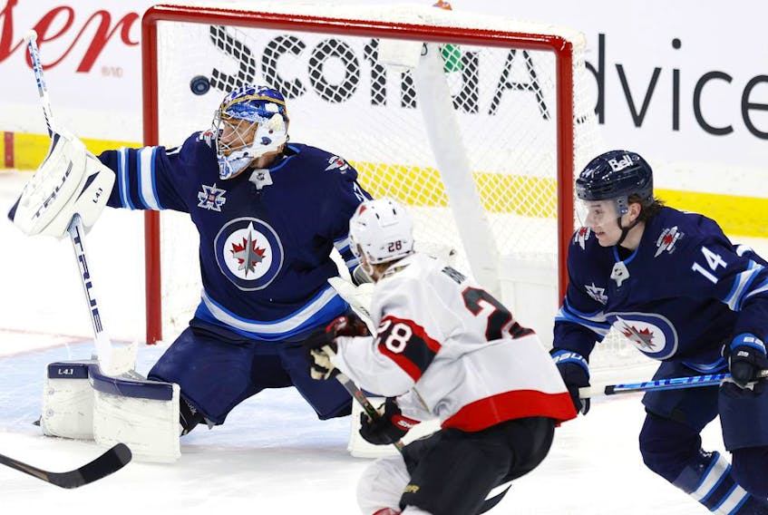 Senators forward Connor Brown watches as a shot by Tim Stuetzle (not in photo) beats Jets netminder Connor Hellebuyck for a goal in the first period of Saturday's game in Winnipeg.