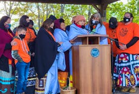 Residential school survivors and loved ones stand on stage at Confederation Landing for a closing prayer at Thursday's ceremony in honour of residential school victims and survivors.