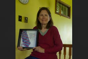 Wolfville children’s author Jan Coates with the framed, autographed pink and blue striped necktie she received as a recipient of the Dr. Strang Community Hero Award. CONTRIBUTED