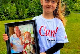 Lily MacDonald, pictured here in the last in-person fundraising walk for Muscular Dystrophy in 2019, holds a picture of her beloved grandfather, the late Bernie McKeough. While COVID has meant that virtual events had to be held the past two years, Lily remains dedicated to raising funds in her grandfather's memory. 