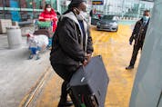  International air travellers load their luggage onto a shuttle bus to take them to one of the quarantine hotels Monday, February 22, 2021 in Montreal.