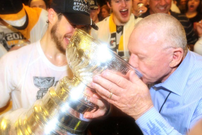 Pittsburgh Penguins general manager Jim Rutherford drinks from the Stanley Cup in the locker room after his team's championship in 2017.